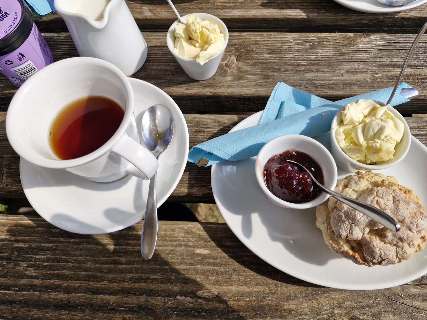 A pot of tea and a scone with jam and cream