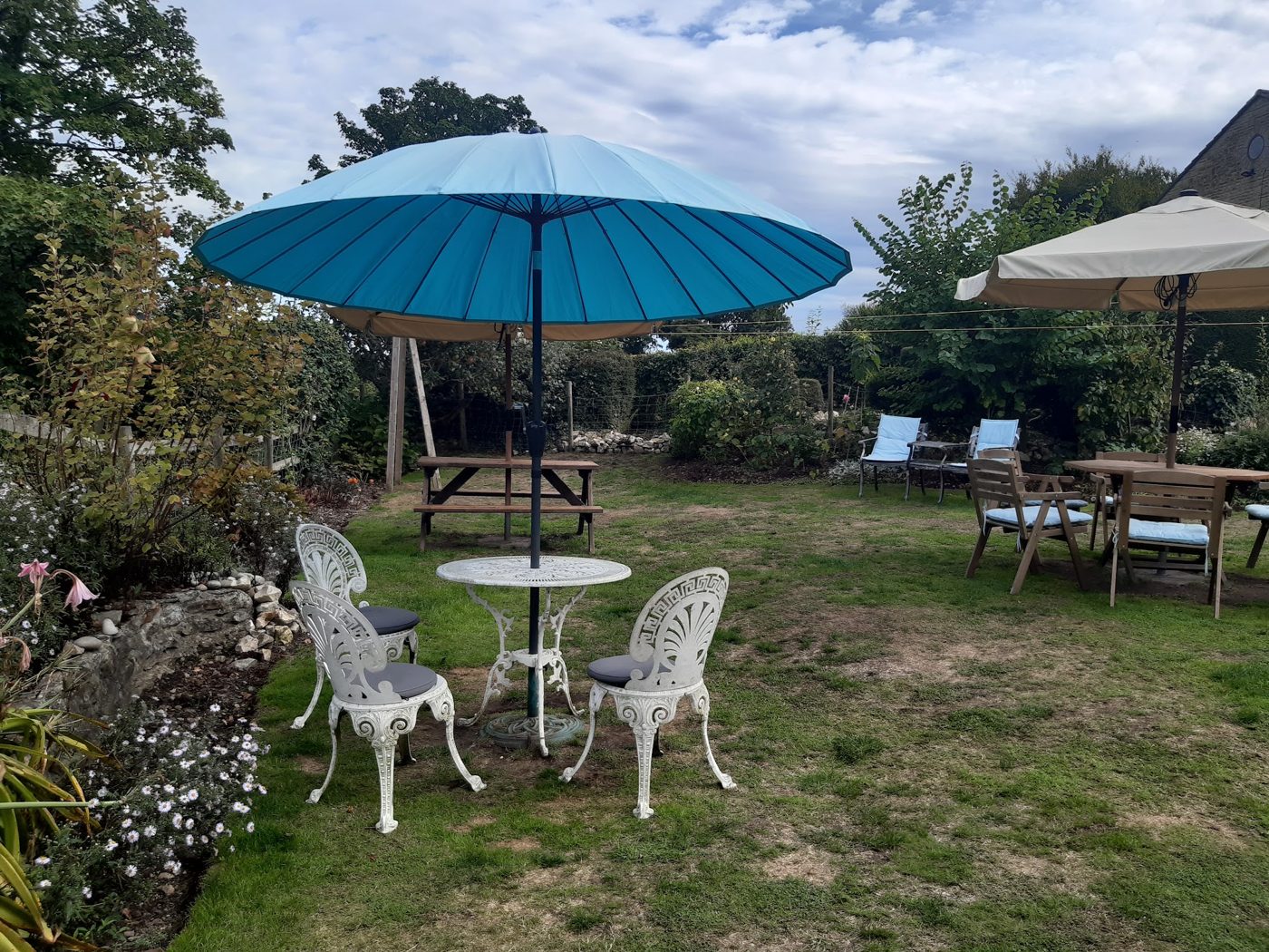 The garden lawn with a blue parasol and white chairs